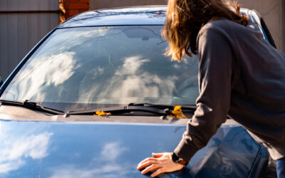 Shocked woman in car with broken windshield and cracks.