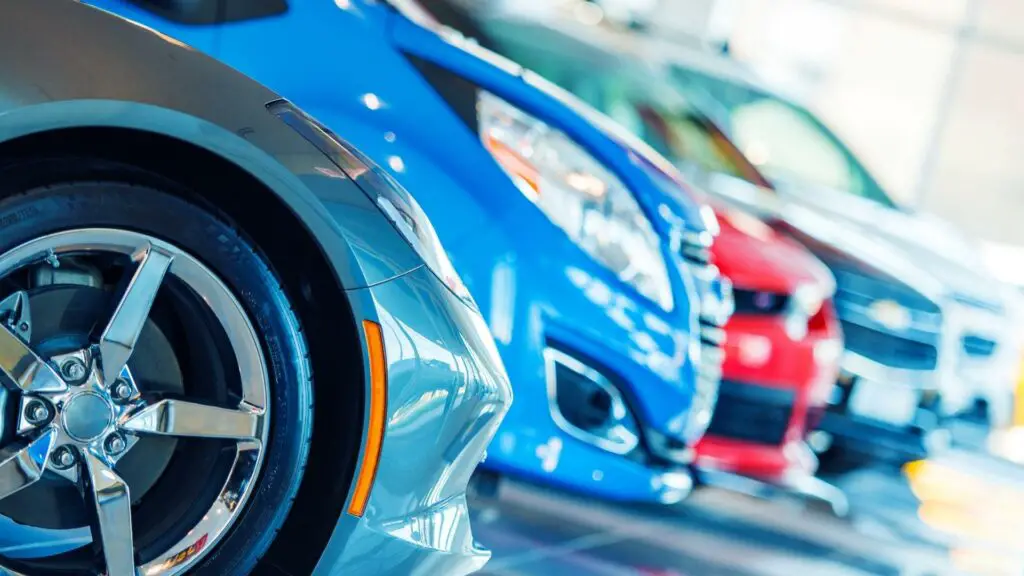 Different colored cars staying in a row, focus on a first grey car, rest cars are blurred.