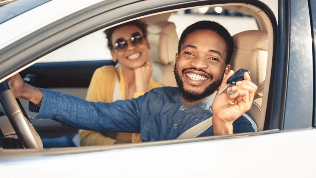 Two People Sit in a Car and Smile